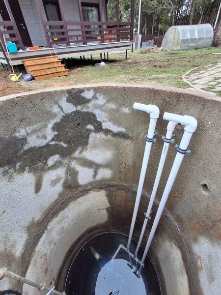 Белые трубы водопровода в шахте колодца у дома